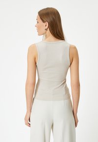 Beige, geribbelde tanktop met een ronde hals en een aansluitend ontwerp. Heeft zijsplitten en een gladde textuur. Geschikt voor casual kleding.