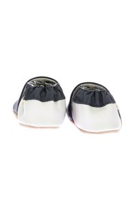 Pantofole in morbida pelle nere e bianche con parte superiore elasticizzata, punte arrotondate e suole in suede beige. Nessun motivo visibile o dettagli hardware.