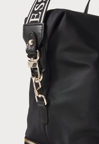 Sort nylon taske med en struktureret overflade, der har hardware i guld-tone, en aftagelig rem og et elegant design. Accentueret med en kontrasterende rem.