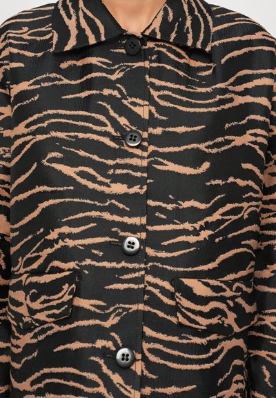 Zwarte en beige tijger gestreepte jas met een kraag, voorzien van een knoopsluiting en voorzakken, gemaakt van een soepele stof.