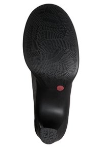 Suela de zapato negra con un patrón de relieve texturizado, que presenta un acento rojo circular. El contorno incluye un tacón redondeado para mayor soporte.