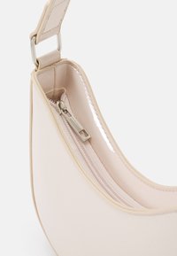 Borsa a mano compatta beige con un esterno in pelle liscia, forma arrotondata e accessori in argento. Dotata di chiusura con zip e una fodera interna lucida.