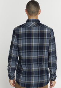 Sötétkék kockás flaneling szürke és mustársárga csíkokkal, gombos mandzsettákkal és klasszikus gallérral, puha, texturált anyagból készült.