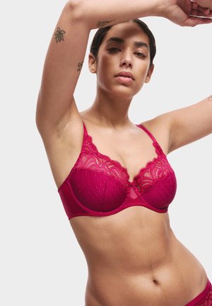 Burgundy lace bra featuring a polka dot pattern, scalloped edges, and a bow detail at the center. Adjustable straps and underwire support.