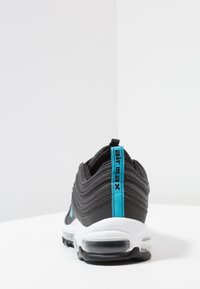 Schwarzer Sport-Schuh mit wellenförmigem Design, blauen Akzenten und transparenter Sohle. Verfügt über einen gepolsterten Kragen und ein markiertes Fersenlabel.