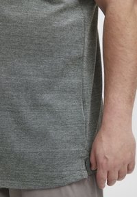 Grå teksturert t-skjorte med en avslappet passform, med sidesømmer og avrundet søm. Stoffet ser lett og pustende ut.