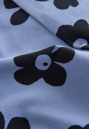 Modrá tkanina s jemnou textúrou, s výraznými čiernymi kvetinovými vzormi a bielymi stredmi, usporiadaná do rozptýleného dizajnu.