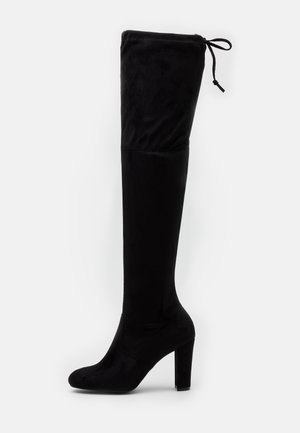 Botte noire à talons hauts au-dessus du genou avec toe arrondi et fermeture par lacet en haut, en tissu doux.