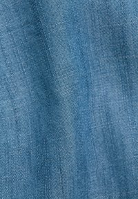 Tissu denim bleu doux avec une texture de tissage diagonal visible et de subtils plis naturels.