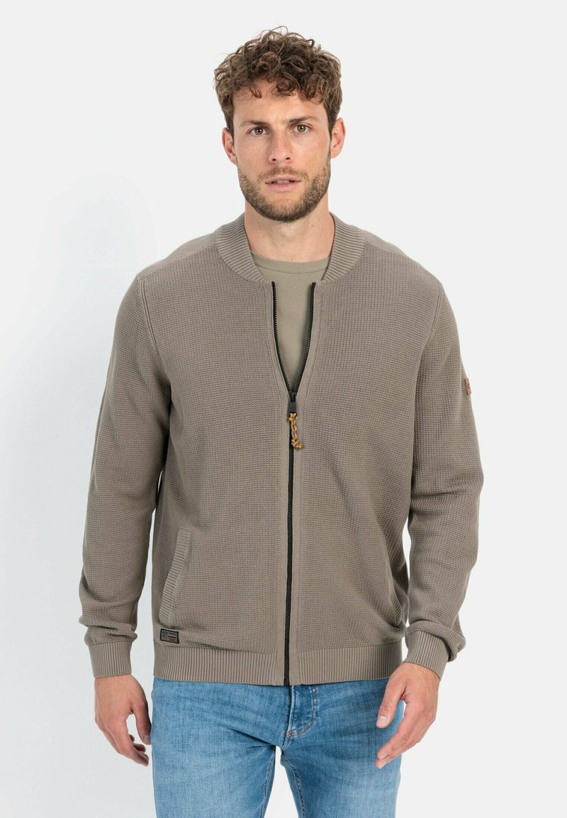 Khaki gebreide cardigan met ritssluiting, textuurstof, geribde manchetten en een staande kraag. Voorzien van zijzakken en een rits met een decoratieve trekker.