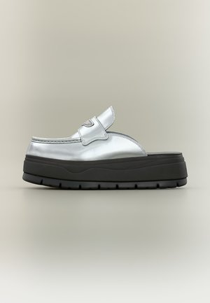Chaussure slip-on en cuir argenté avec semelle épaisse en caoutchouc noir et crampons larges, vue de profil sur fond neutre.