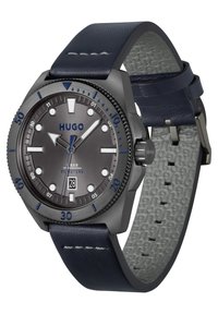 Reloj Hugo con esfera gris, acentos azules, caja de acero inoxidable negro y correa de cuero navy con un reverso texturizado en gris.