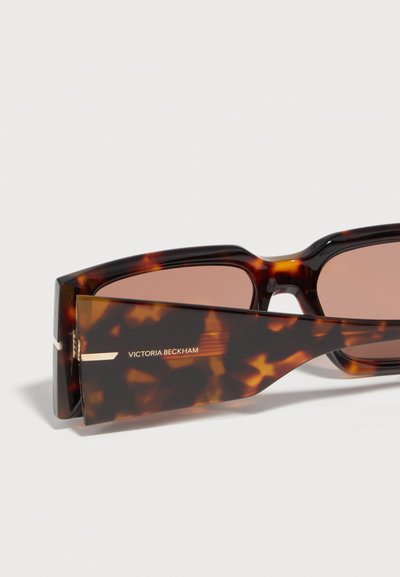 Ορθογώνια γυαλιά ηλίου με σχέδιο κέλυφος χελώνας, καφέ φακούς και πλαϊνά μέρη ευρείας έκτασης, με λογότυπο "Victoria Beckham" σε χρυσά γράμματα.