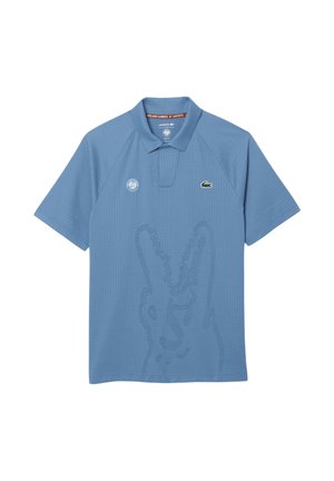 Hellblaues Lacoste-Poloshirt mit dezentem, geprägtem Krokodildesign, Roland-Garros-Logo auf der Vorderseite und kurzen Ärmeln.