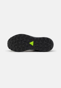 Semelle en caoutchouc noir avec un motif texturé pour une meilleure adhérence, accentuée par un triangle jaune central près du talon. Construction durable.