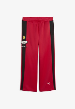 Czerwone spodnie dresowe z czarnymi paskami po bokach, elastyczną talią, kieszeniami na suwak, logo Ferrari i białym logo Puma w pobliżu lewego kostki.