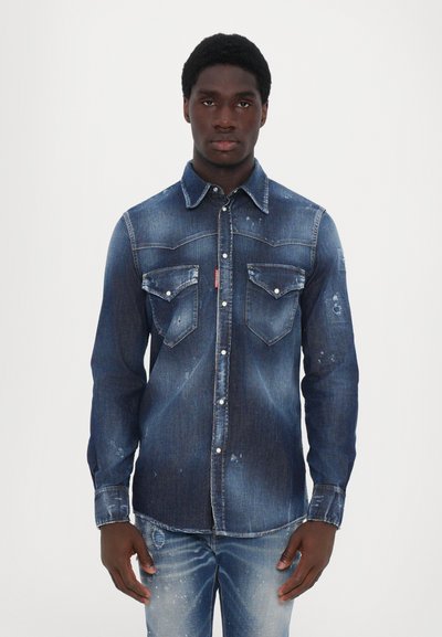 Jeanshemd mit dunklem Blau-Waschung, spitzem Kragen, Taschen vorne und verwaschenen Details. Lange Ärmel mit Knopfmanschetten.
