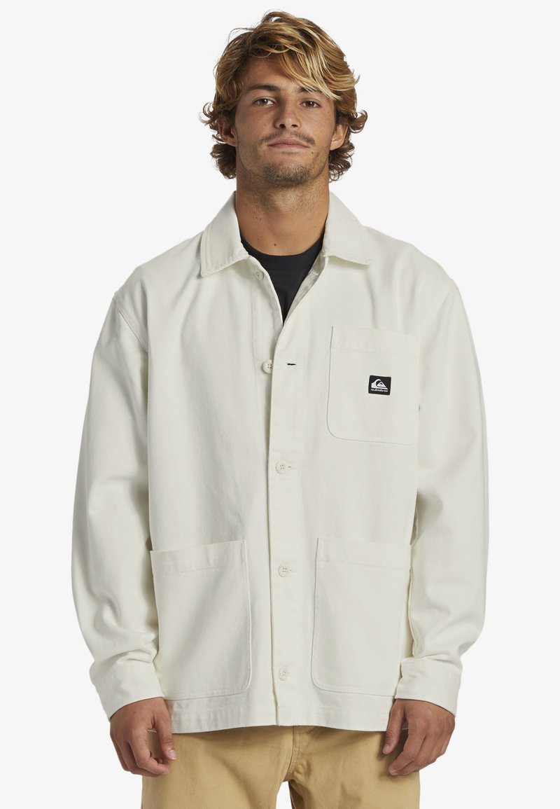 Lightweight cream jacket with a collared neck, button closure, and front pockets. Features a small black logo on the left chest pocket.