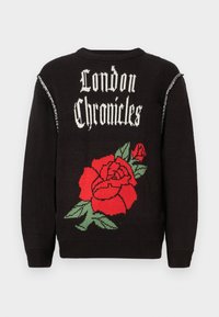 Zwarte gebreide trui met de tekst "London Chronicles" in het wit, en een groot rood rozenontwerp met groene bladeren op de achterkant.
