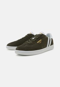 Sneaker verde oliva in materiale scamosciato, con suola in gomma bianca, strisce bianche a contrasto e dettagli in rete imbottita sulla linguetta e sul colletto.