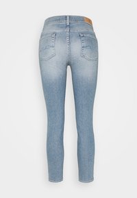 Jeans de mezclilla azul claro con un diseño ajustado, que cuentan con dos bolsillos traseros y un patrón de costura, textura suave y dobladillo limpio.