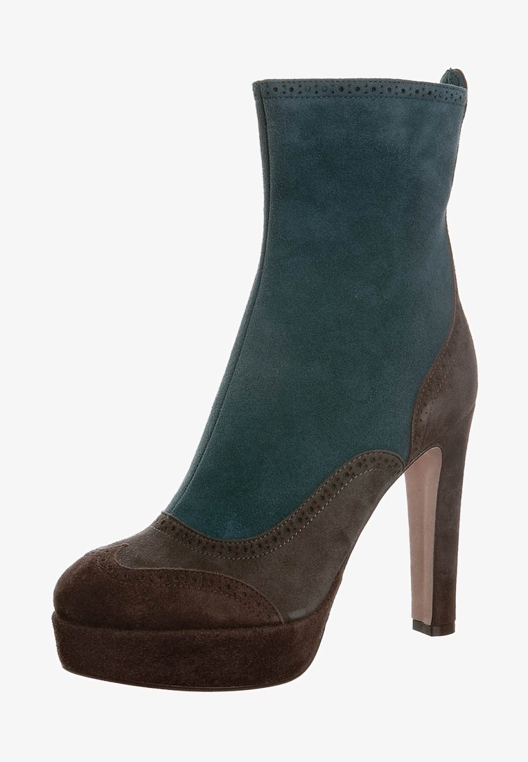 Bottine à talon haut combinant du daim turquoise et brun foncé avec des perforations décoratives et une semelle plateforme.