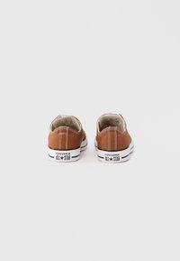 Καφετιά πάνινα αθλητικά παπούτσια με λευκές λαστιχένιες σόλες και μαύρες λεπτομέρειες. Διαθέτουν ραμμένη διακόσμηση και λογότυπο στη φτέρνα. Σχεδίαση χαμηλής κοπής.