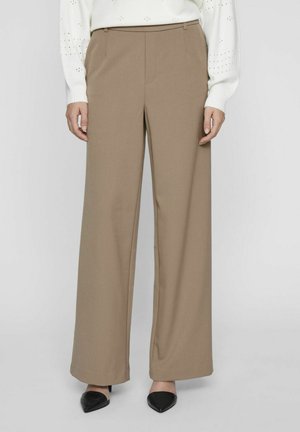 Tan wide-leg trousers made of smooth fabric, featuring a high waist, side pockets, and a tailored fit. Shoes have a pointed toe and black color.