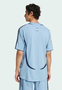Light blue sports jersey with short sleeves, featuring navy accents, a subtle striped texture, and a logo at the back.