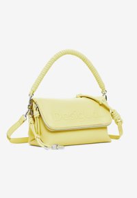 Borsa a mano gialla in pelle con superficie strutturata, chiusura con zip e manico intrecciato. Presenta il logo "Desigual" in rilievo sulla parte frontale.
