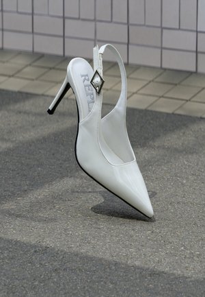 Weißer High-Heel mit spitzer Kappe, Slingback-Design und metallischem Diamant-Akzent am Riemen. Glänzendes Lackleder-Finish.