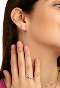 Pendientes en forma de aro multicolores con piedras y un anillo a juego, que presentan un fino diseño metálico con superficies suaves y pulidas.