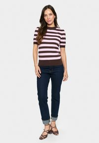 Un pull à manches courtes en tricot à rayures roses et brunes, associé à un jean foncé et des ballerines à imprimé animal.