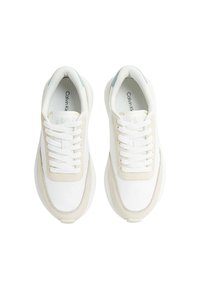 Zapatillas blancas y crema con un upper texturizado, diseño de cordones y cuello acolchado. Presentan un sutil acento azul en el talón.