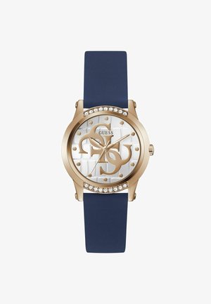 Gouden horloge met een witte gestructureerde wijzerplaat, een marineblauwe silicone strap, kristalaccenten en grote merkletters in het midden.