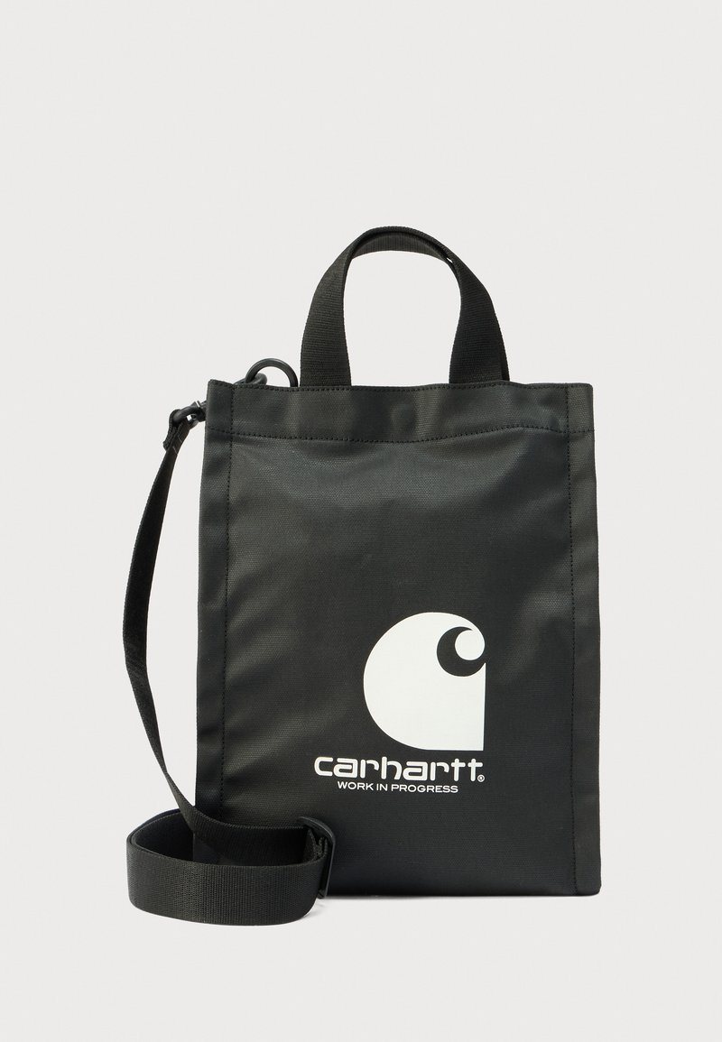 Μαύρη υφασμάτινη τσάντα tote με κοντά επάνω χερούλια και αποσπώμενο ιμάντα ώμου. Διαθέτει μεγάλο λευκό λογότυπο Carhartt στην πρόσοψη.