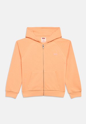 Pfirsichfarbener Hoodie mit Reißverschluss vorne, gerippten Bündchen und zwei Vorderentaschen. Mit einem kleinen Logo auf der Brust und einer gemütlich gefütterten Kapuze.