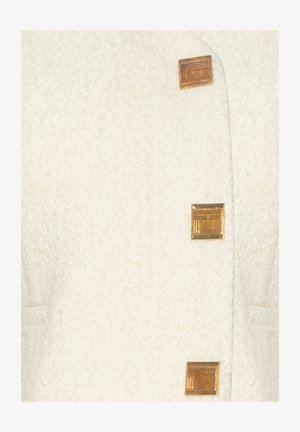 Weißer, strukturierteter Mantel mit drei quadratischen goldenen Knöpfen mit Linienmustern. Zwei Taschen an den Seiten sind vorne sichtbar.