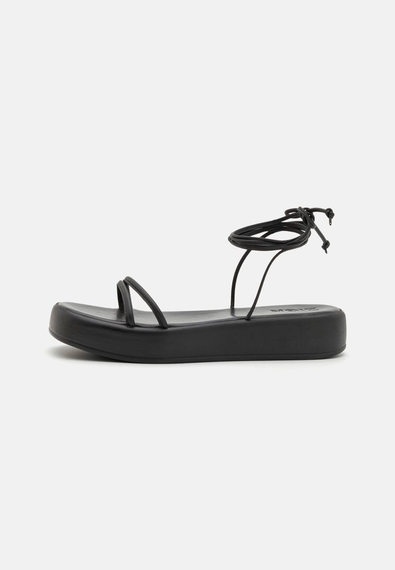 Mustad mustad sandaalid laia tallaga, õhukeste rihmadega ja reguleeritava sidumisega pahkluu ümber. Sile tekstuur ja minimalistik disain.
