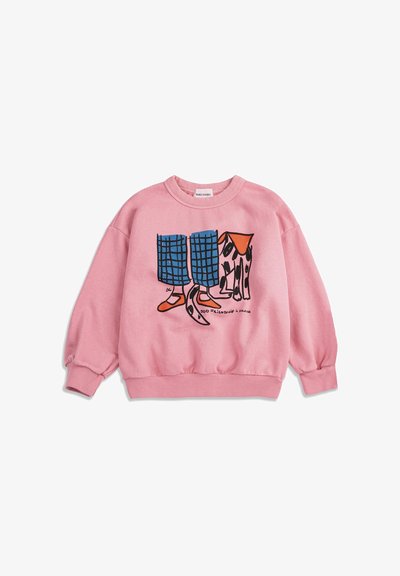 Sweat-shirt rose avec une illustration d'un pantalon à carreaux bleu, des chaussures orange et un chien tacheté debout côte à côte, le texte indique "Amitié canine."
