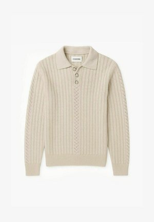 Beige ribbad stickad polo-tröja med krage, tre knappar och diamanter accentmönster ner i mitten. Mjuk textur med långa ärmar.