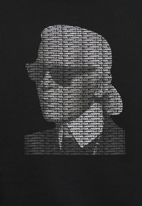 Silhouette di una persona che indossa occhiali da sole, formata da ripetute scritte bianche "KARL LAGERFELD" su uno sfondo nero.