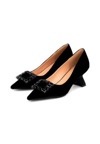 Zapatos de salón bajos de terciopelo negro, con puntera puntiaguda y adornos de gemas negras rectangulares en la parte frontal.