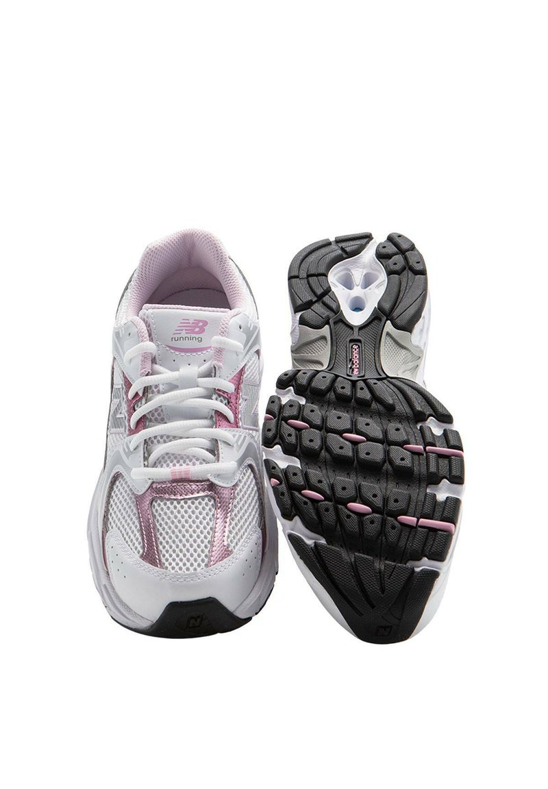 Zapatillas de deporte blancas con parte superior de malla, acentos en rosa y suela de goma negra con un patrón texturizado. Cintas blancas y logotipo en el costado.