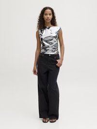 Top senza maniche di metallo argento con una silhouette aderente, abbinato a jeans neri a gamba larga a vita alta e sandali neri piatti.