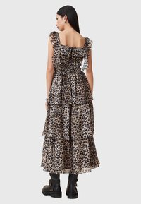 Abito maxi con stampa leopardata, dotato di spalline con balze e strati a balze, caratterizzato da un corpino arricciato, abbinato a stivali neri alla caviglia.