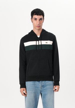 Black zip-up hoodie featuring a color-blocked design with green and white stripes across the chest, kangaroo pockets, and a drawstring hood.