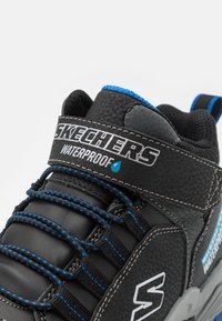 Schwarze wasserdichte Sneaker mit blauen Akzenten, ausgestattet mit verstärktem Schnürdesign, gepolstertem Schaft und strukturiertem Obermaterial aus Synthetik.