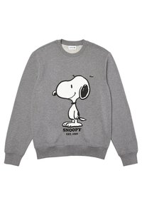 Sweat-shirt gris avec un motif Snoopy en noir et blanc, texte "SNOOPY EST. 1950" et petit logo crocodile vert de Lacoste.