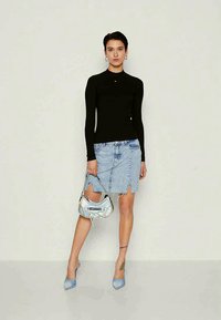 Black long-sleeve top, light blue denim skirt with side slits, iridescent handbag, and light blue pointed heels. Smooth and structured textures.